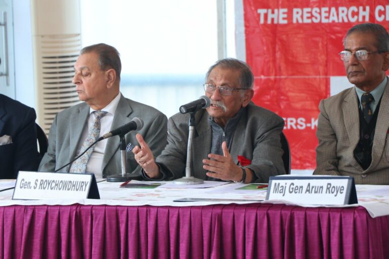 Three panellists at the CENERS-K table below the centre's red banner, with name plates for Gen S Roychowdhury and Maj Gen Arun Roye; the centre panellist speaks with both hands raised.