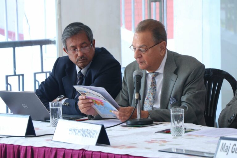 Gen S Roychowdhury studying a printed map with a colleague at the CENERS-K panel table, an open laptop in front of them.
